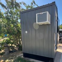 A small shed with a window air conditioner on the side of it.