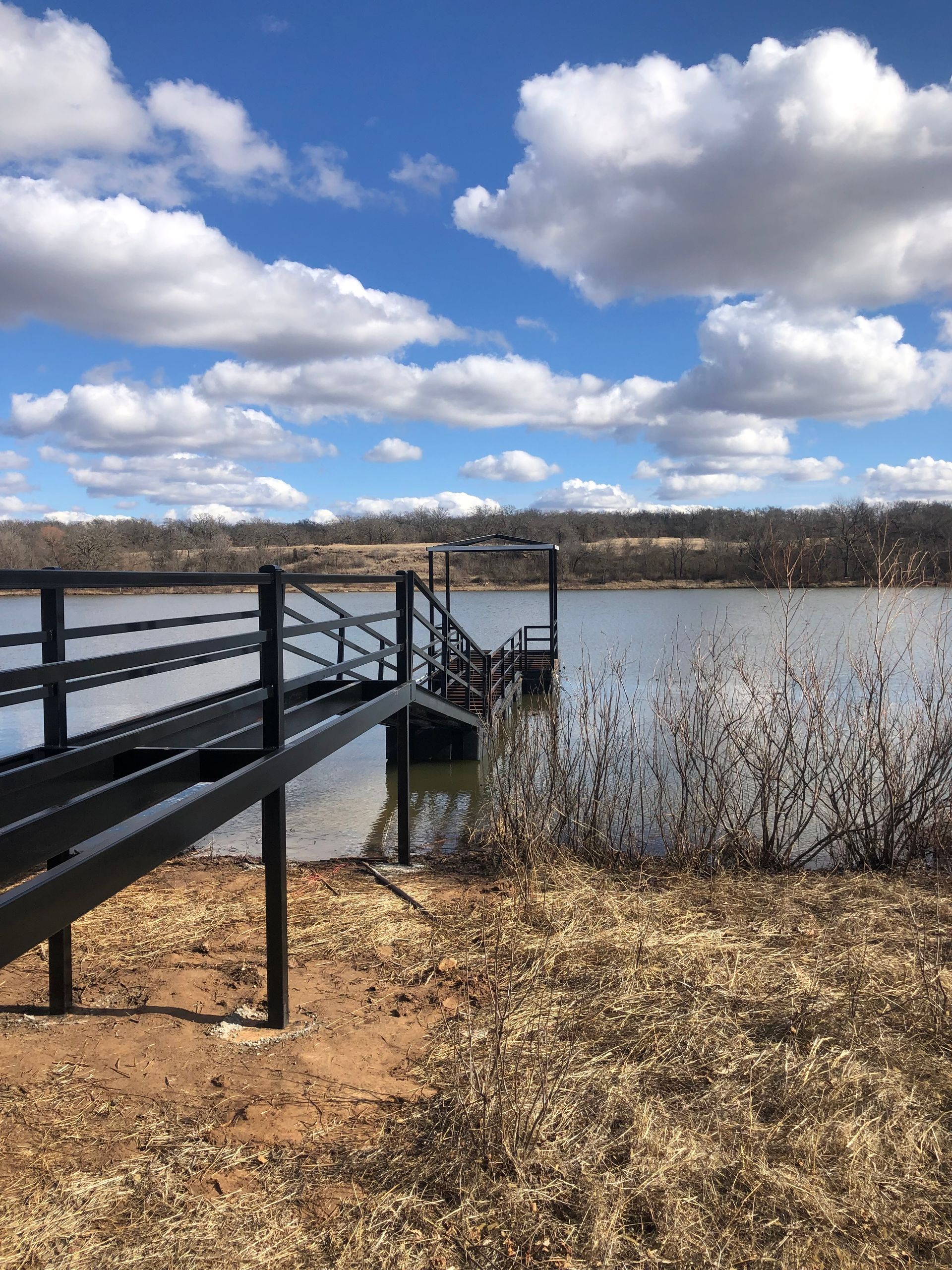 A dock with a ramp leading to a lake on a cloudy day.