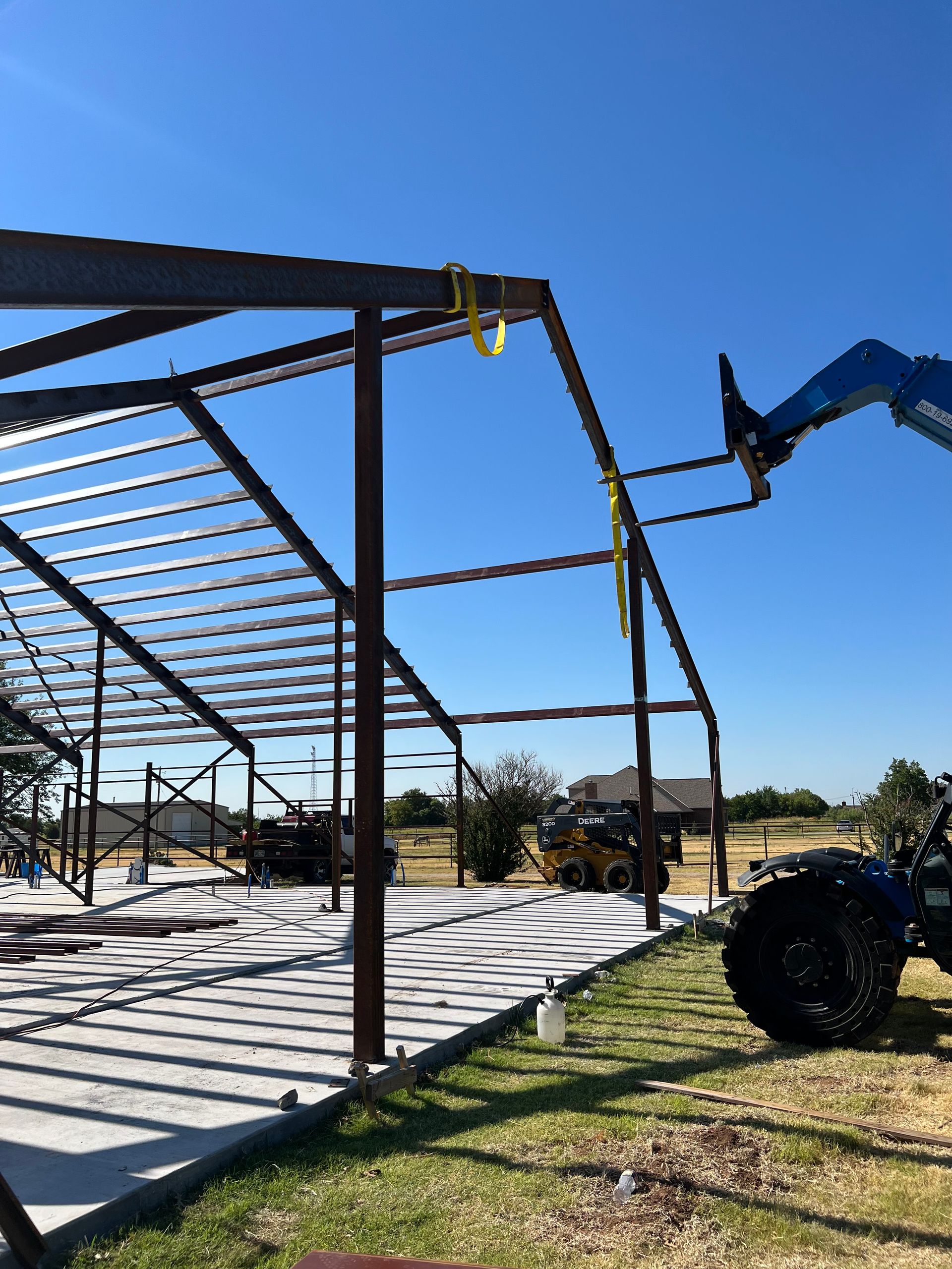 A tractor is lifting a metal structure in a field.