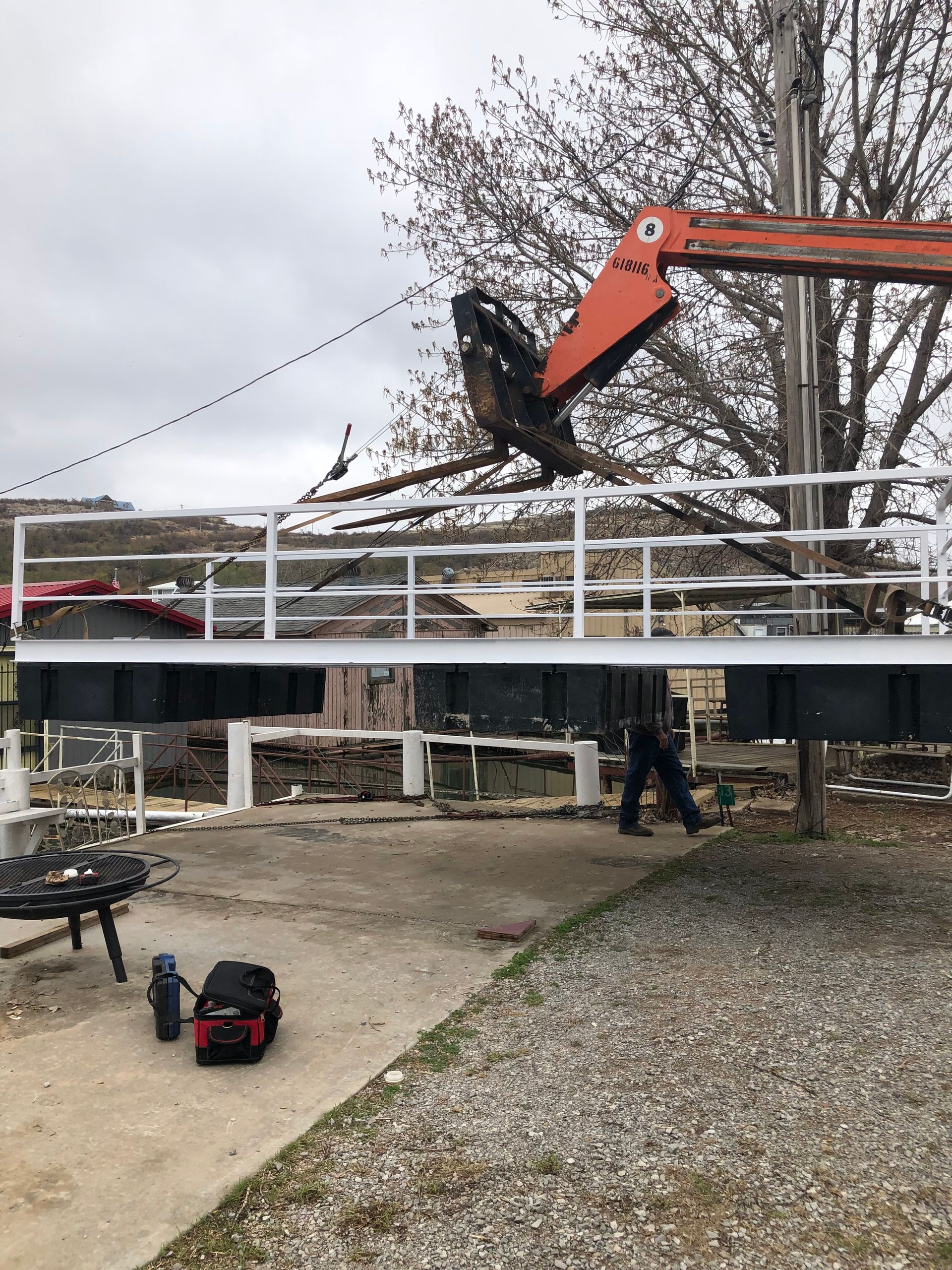 A crane is lifting a tree branch over a bridge.