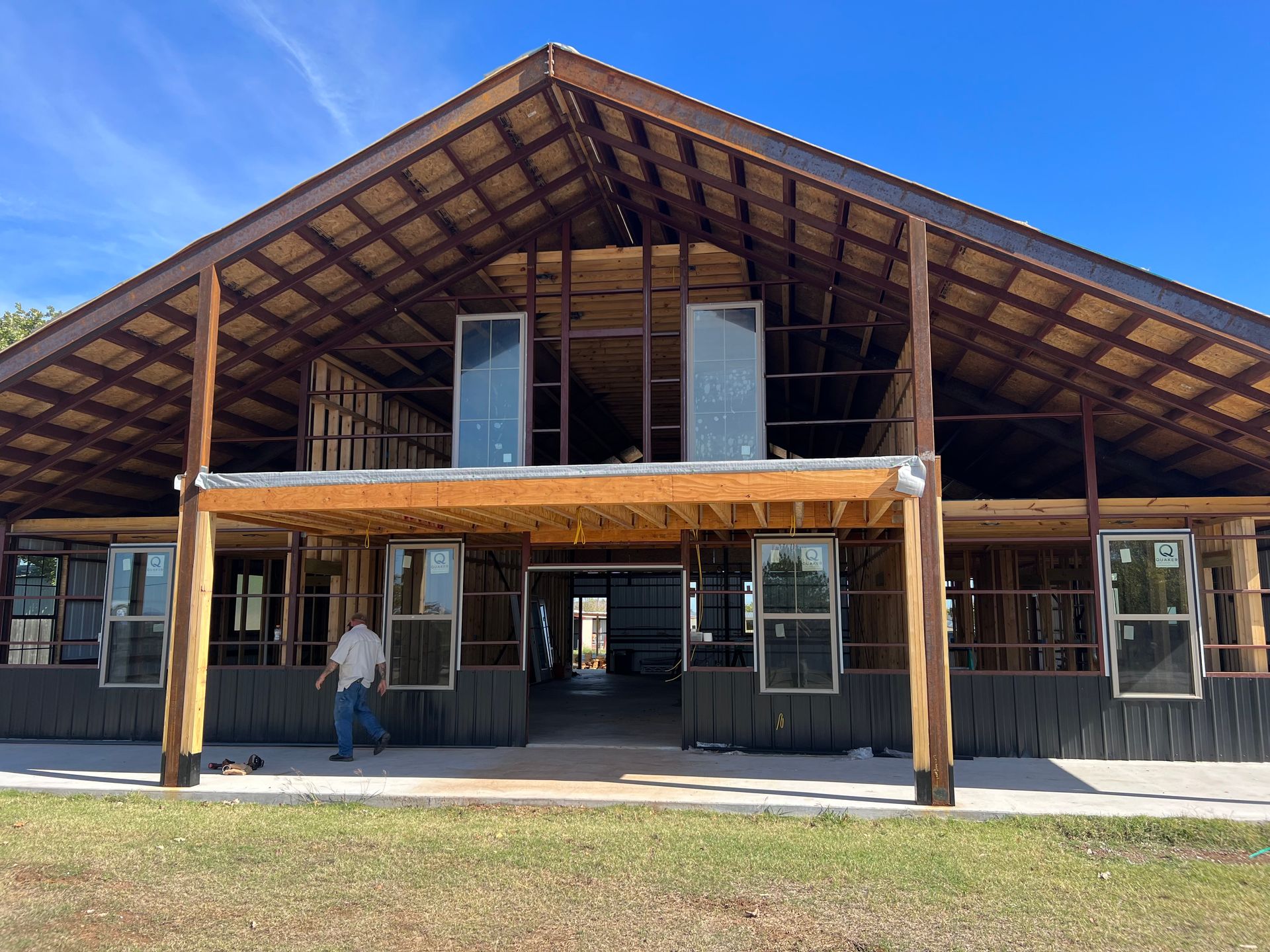 A man is standing in front of a large wooden building under construction.