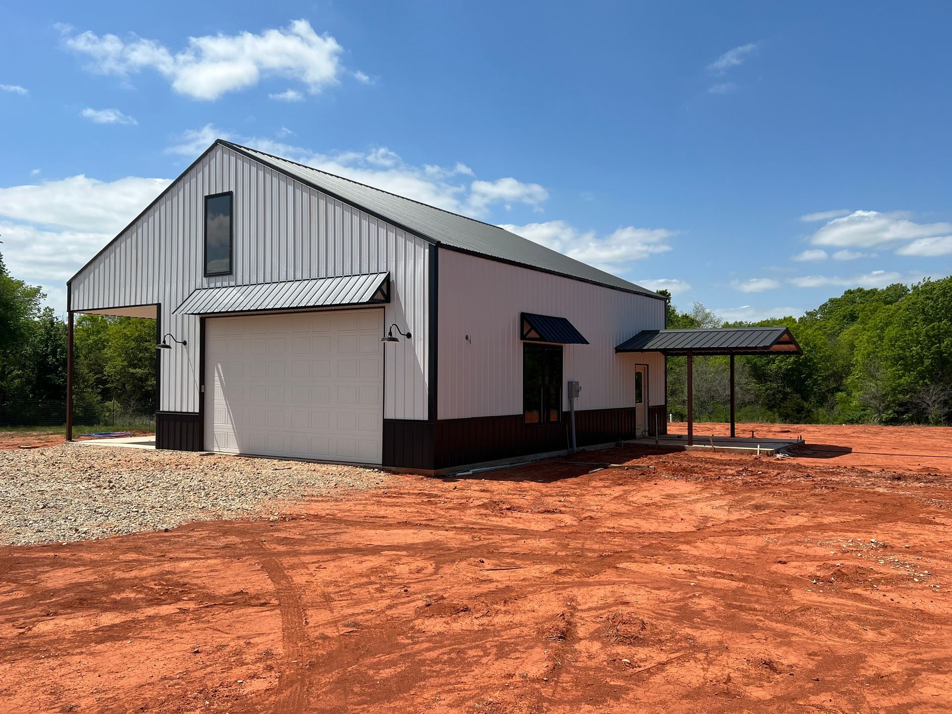 A white barn is sitting in the middle of a dirt field.