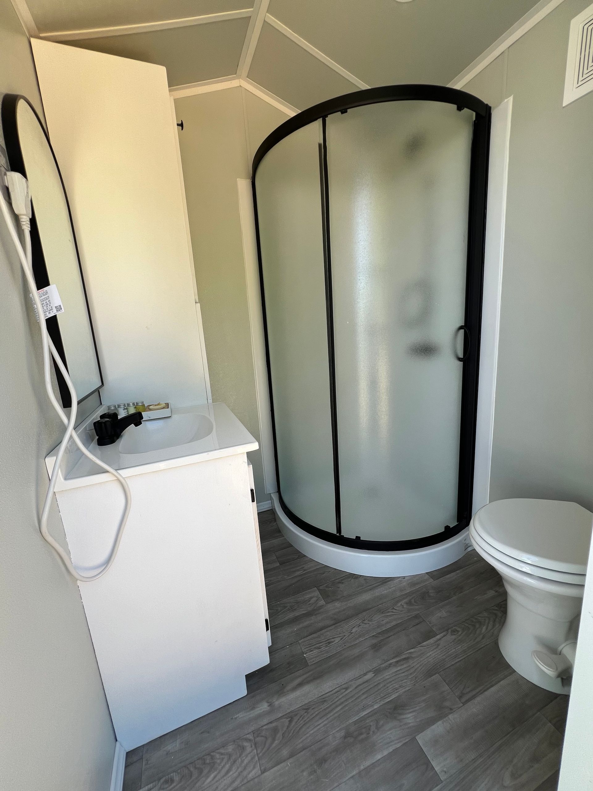 A bathroom with a toilet , sink , shower and mirror