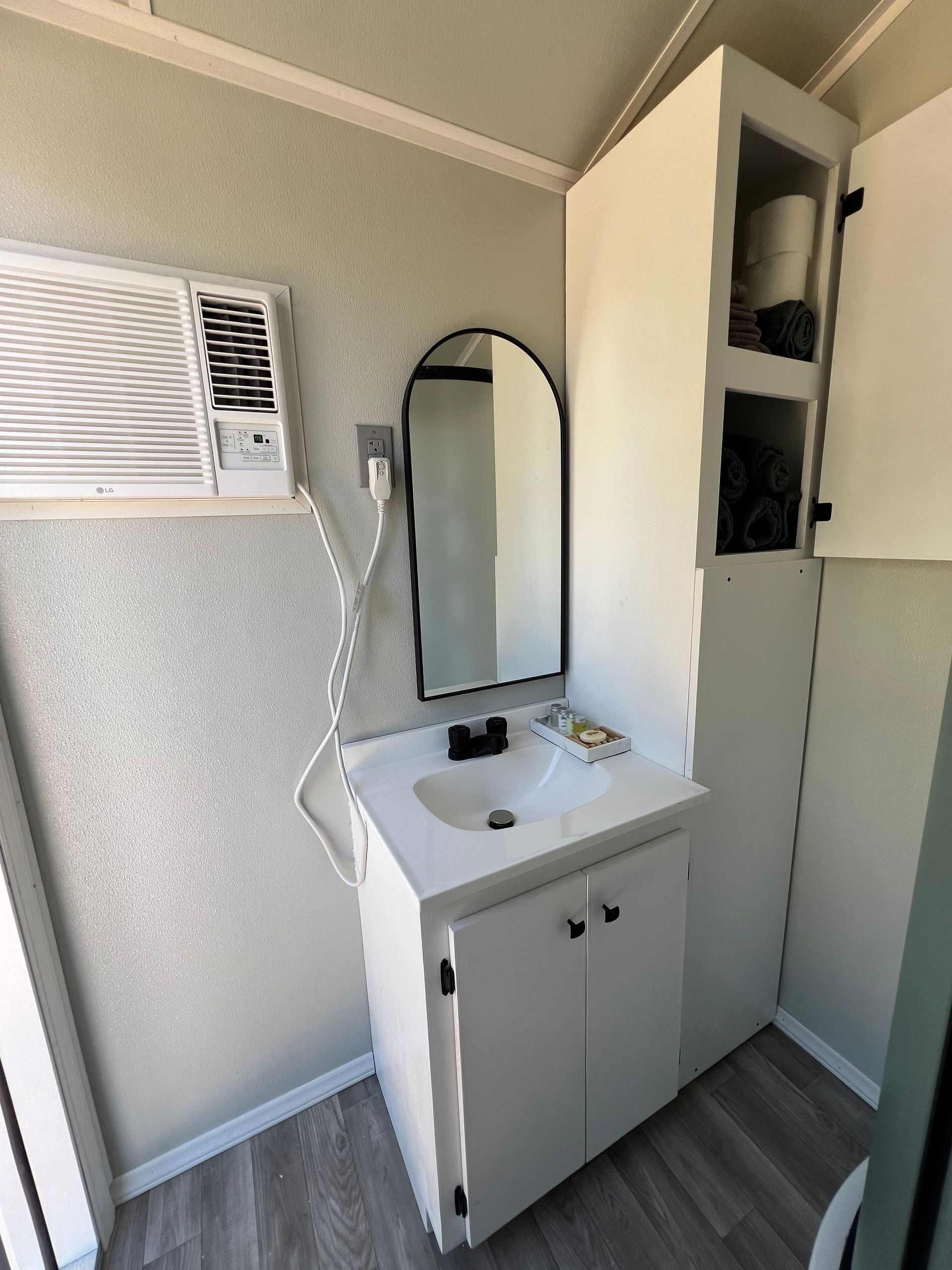 A bathroom with a sink a mirror and an air conditioner