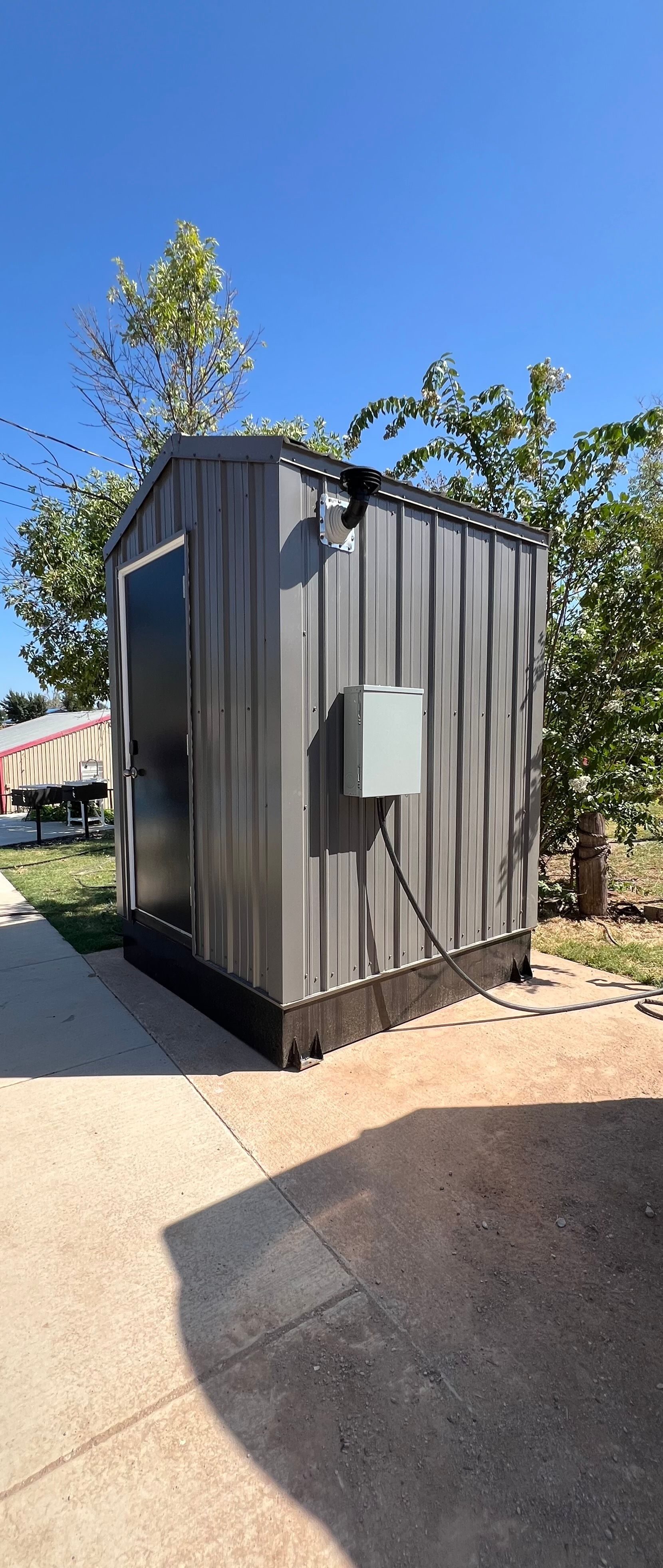 A small shed with a box on the side of it is sitting on the side of the road.