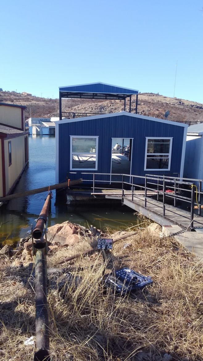 A blue houseboat is docked next to a body of water.
