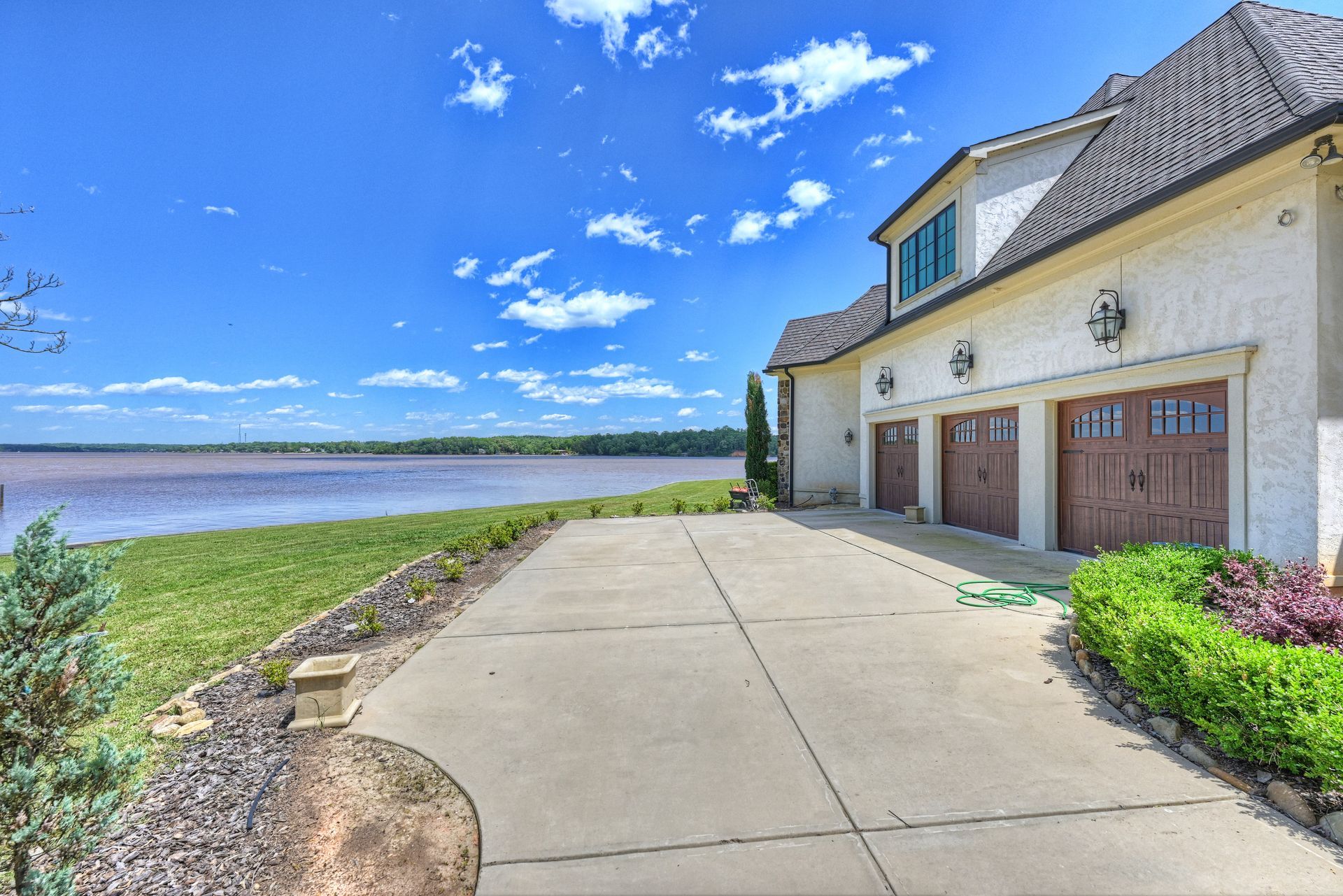 a large white house with brown garage doors overlooking a lake | Charlotte, NC | Harland Building Group 