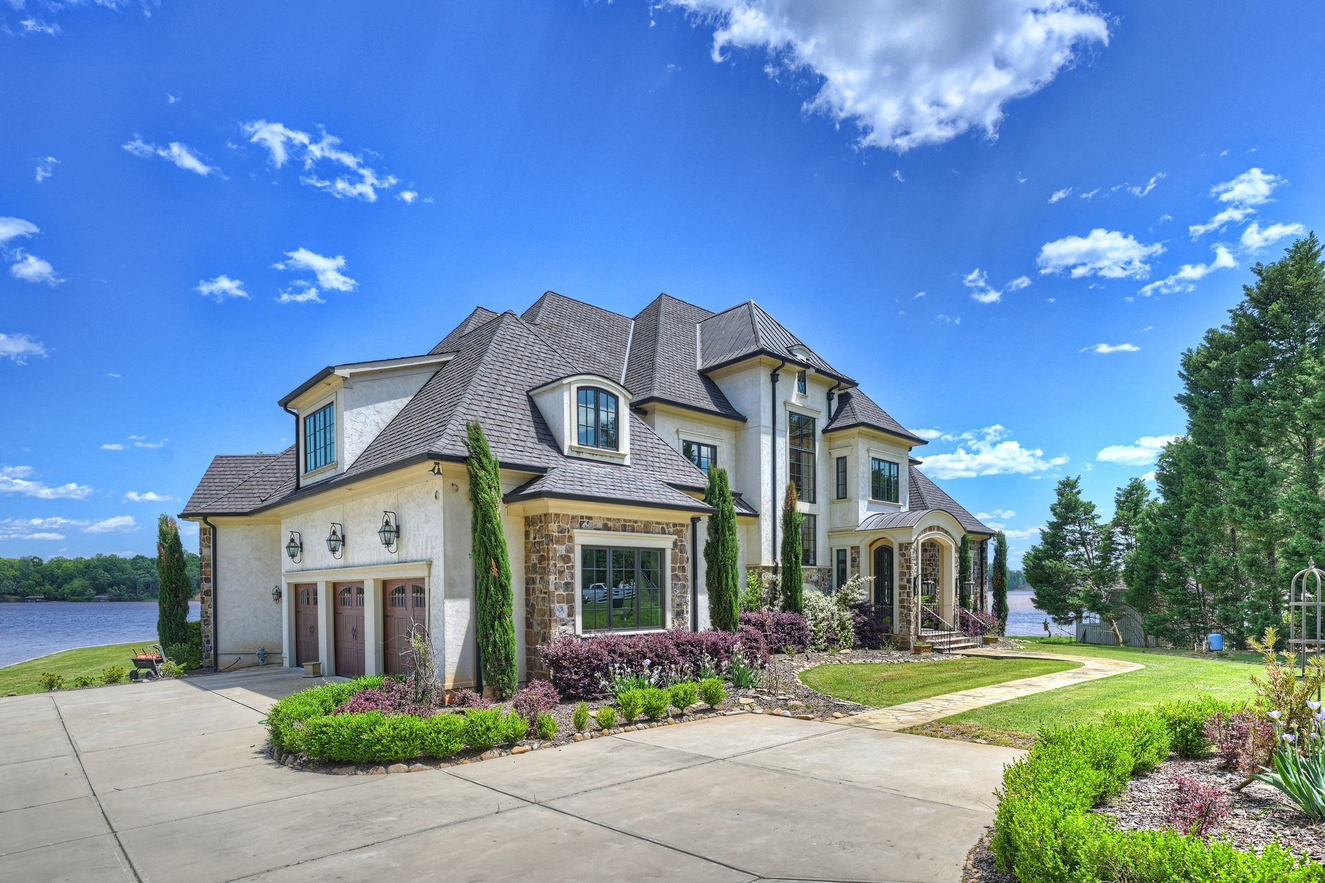 a large white house sits on the shore of a lake | Charlotte, NC | Harland Building Group 