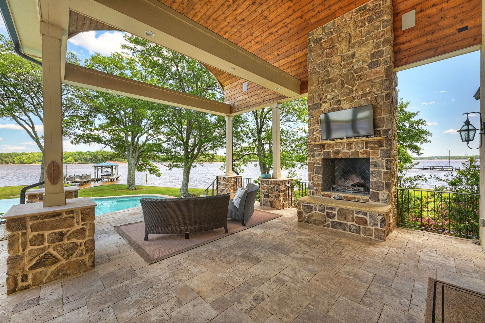 a patio with a fireplace and television overlooking a lake | Charlotte, NC | Harland Building Group 