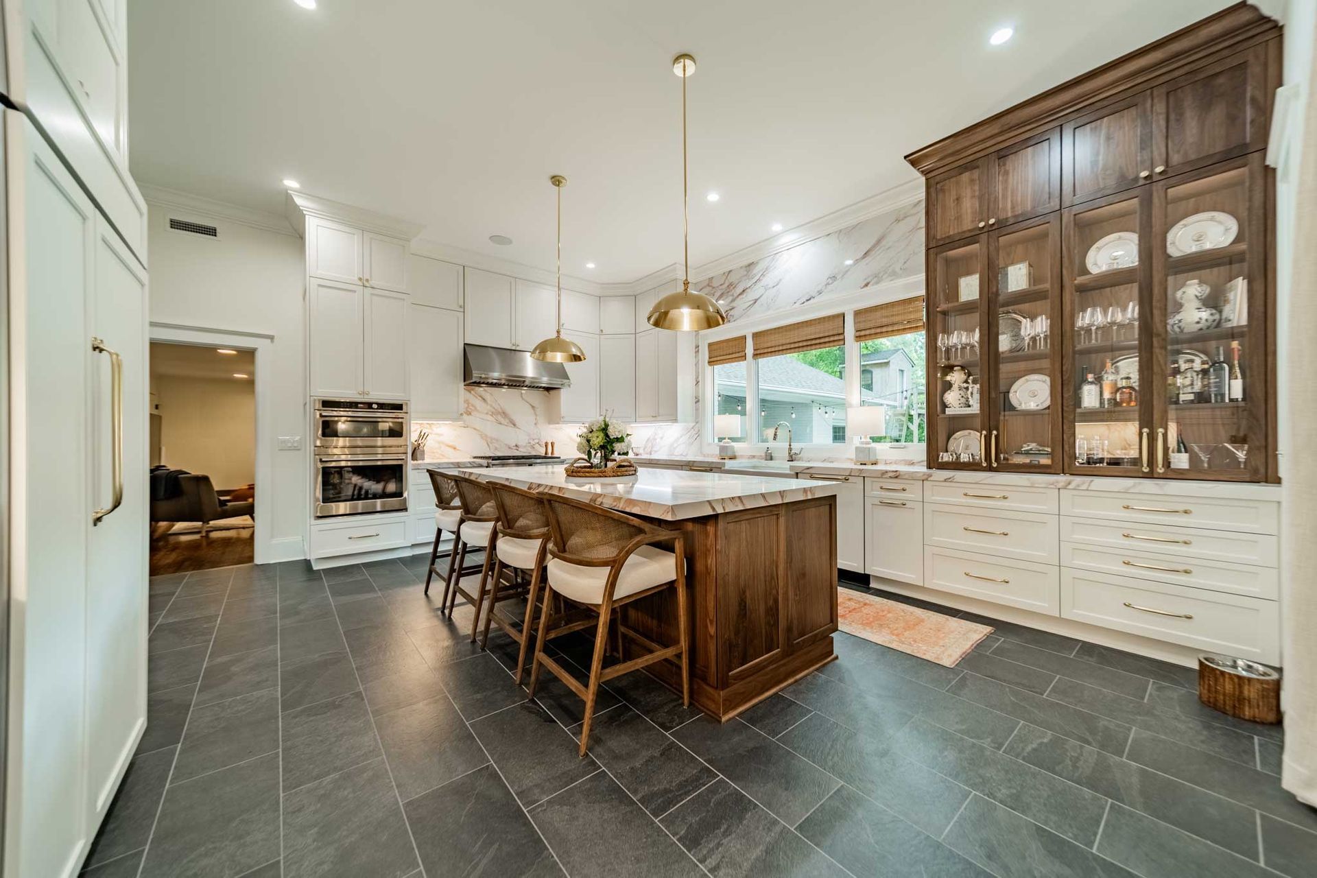 A kitchen with a large island , stools and a refrigerator.