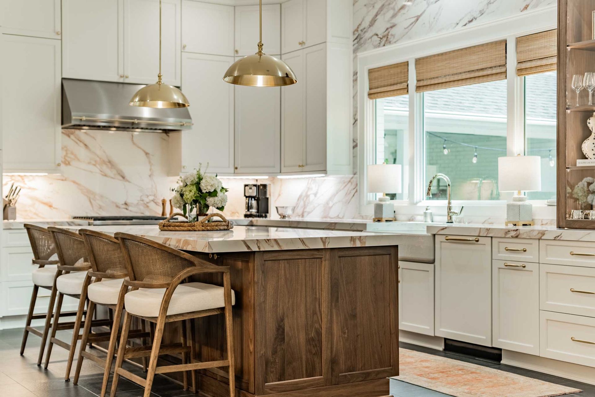 A kitchen with white cabinets , a large island , and wicker chairs.