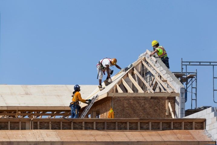 Construction workers building a roof on a sunny day.