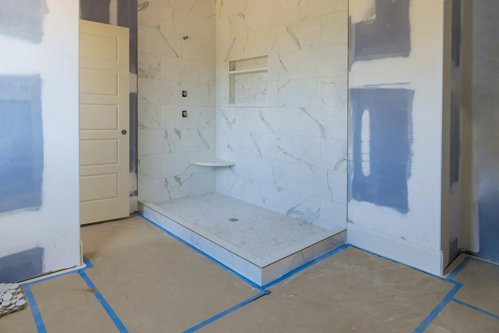 Partially renovated room with taped floor, patchy drywall, and a small raised platform in the center