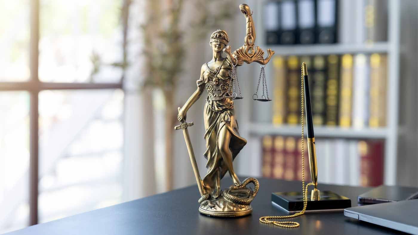 A statue of justice is sitting on a desk next to a scale of justice.