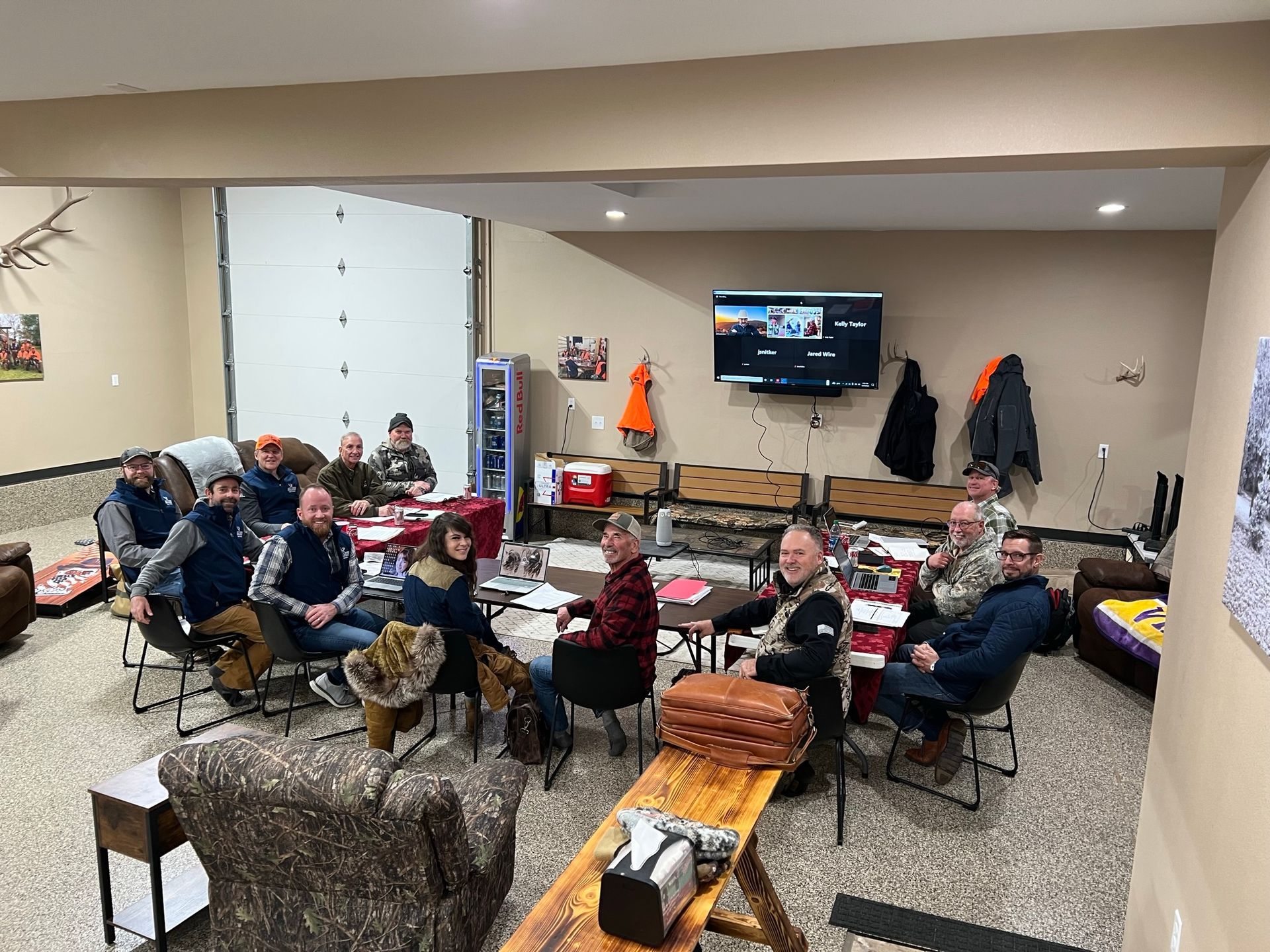 A group of people are sitting around tables in a living room.
