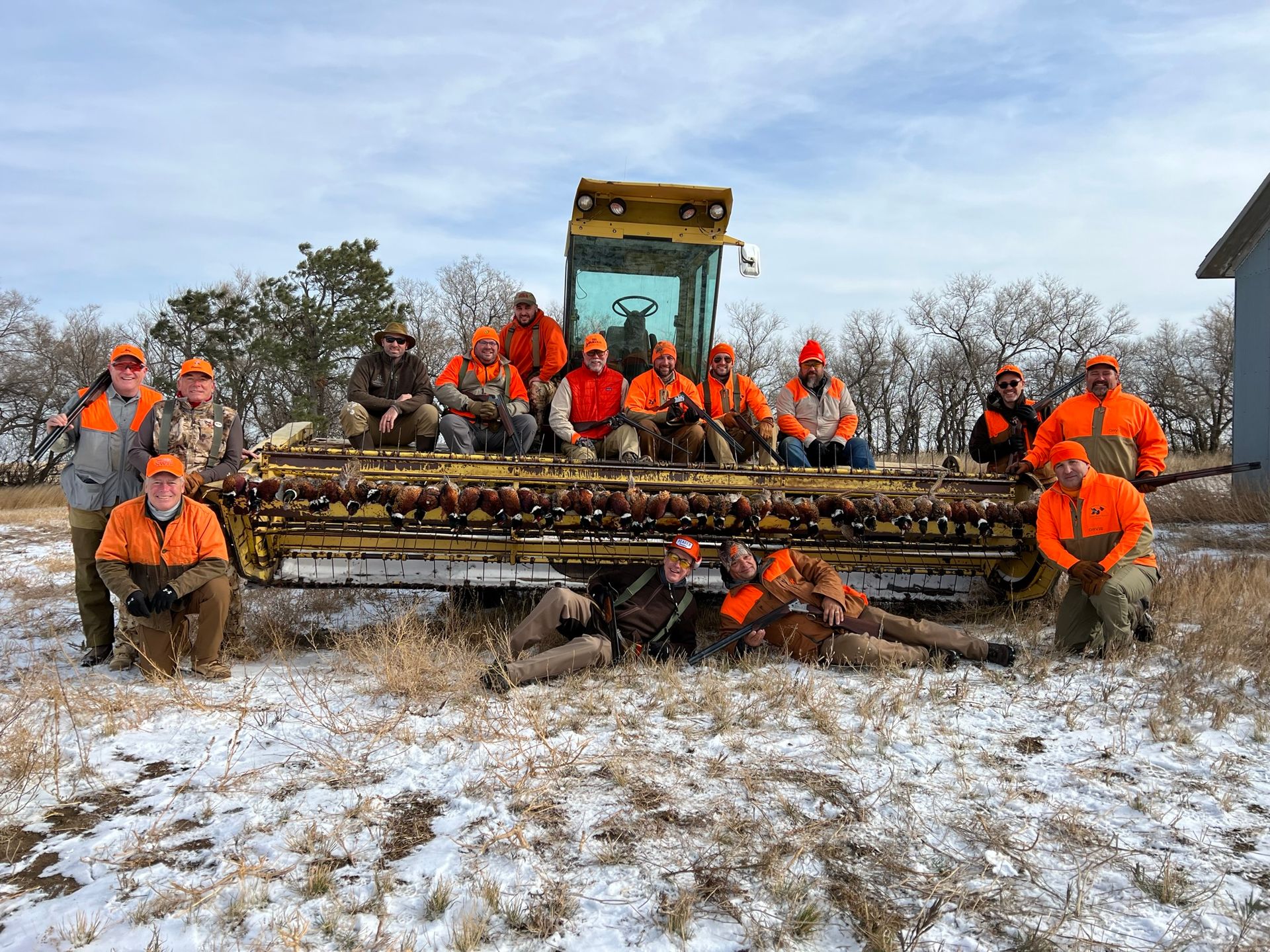 A group of hunters are posing for a picture in front of a tractor.