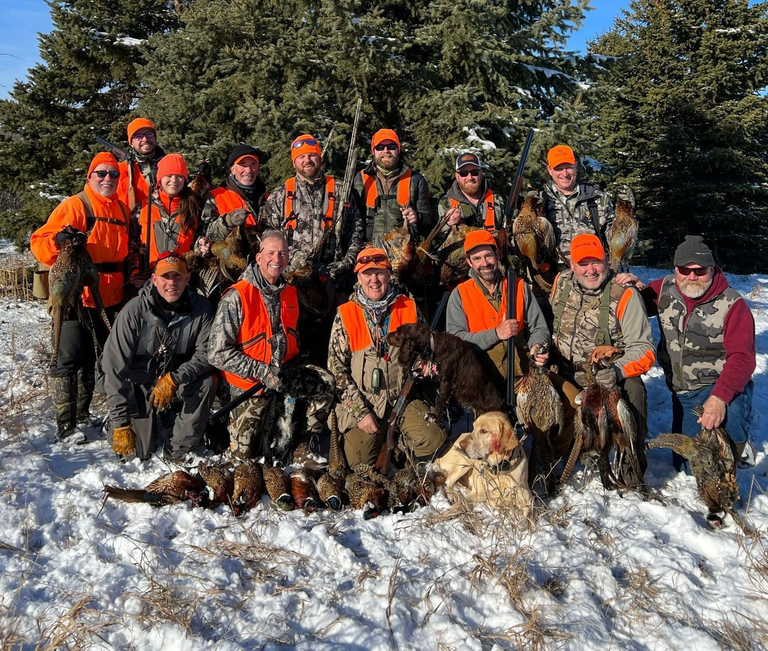 A group of hunters are posing for a picture in the snow.