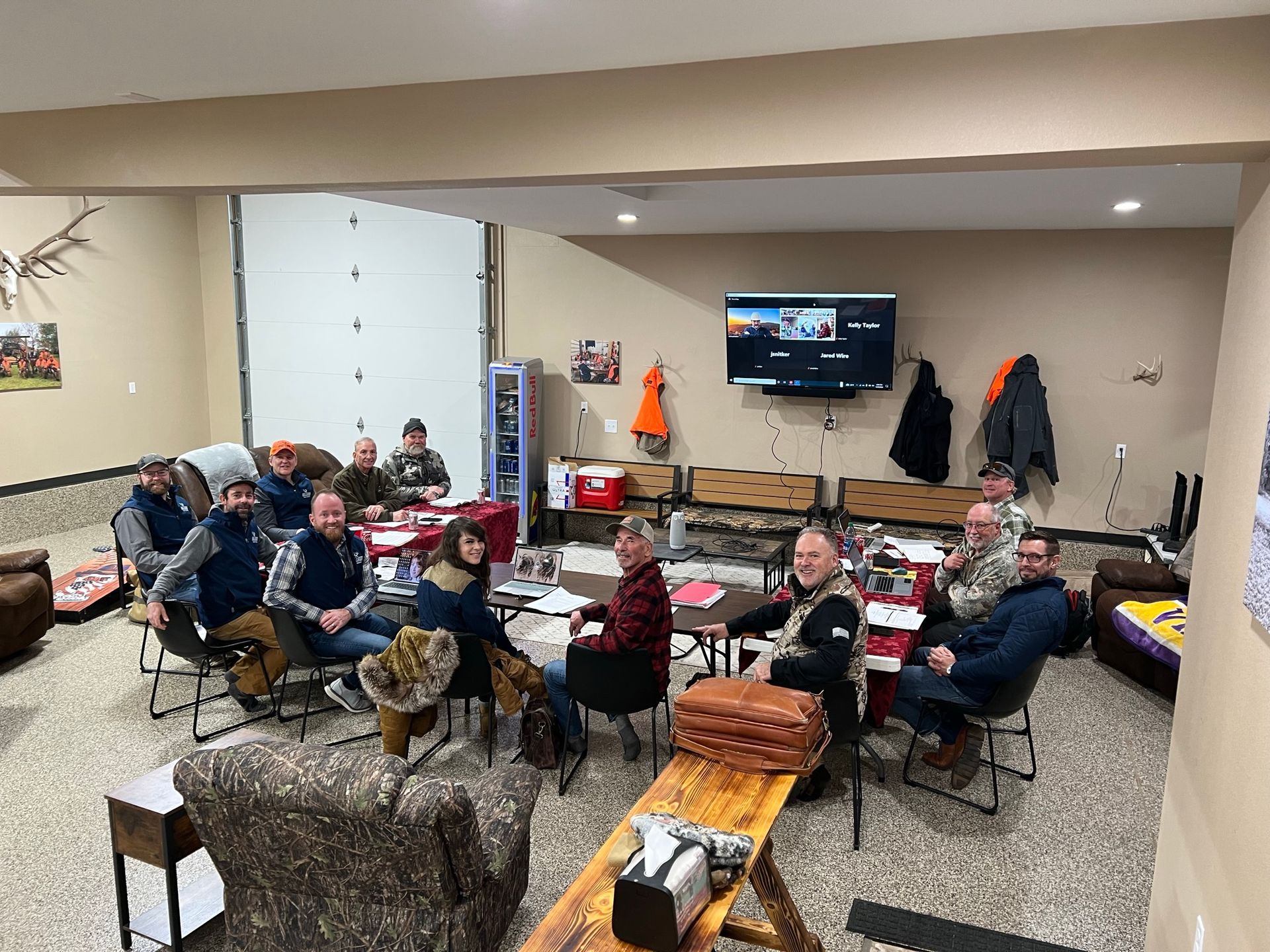 A group of people are sitting around tables in a living room.