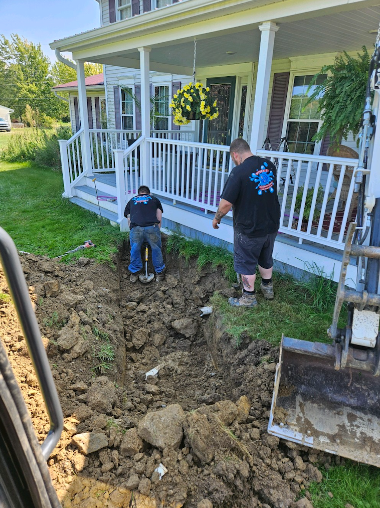 Workers digging trench in a front yard to install new sewer line.