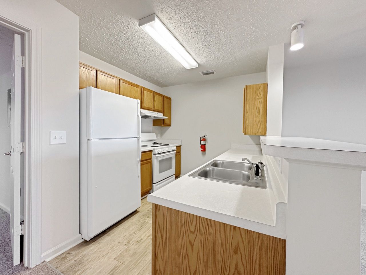 Kitchen with white appliances, wooden cabinets, and white countertops.
