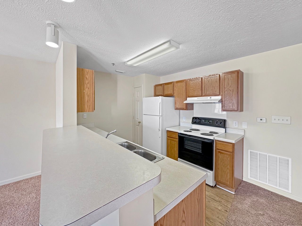 Kitchen with brown cabinets, white appliances, and a breakfast bar.