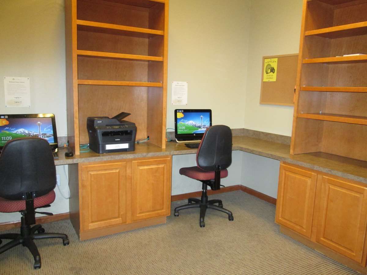 Computer stations in a room with wooden cabinets, shelving, and two computer chairs.
