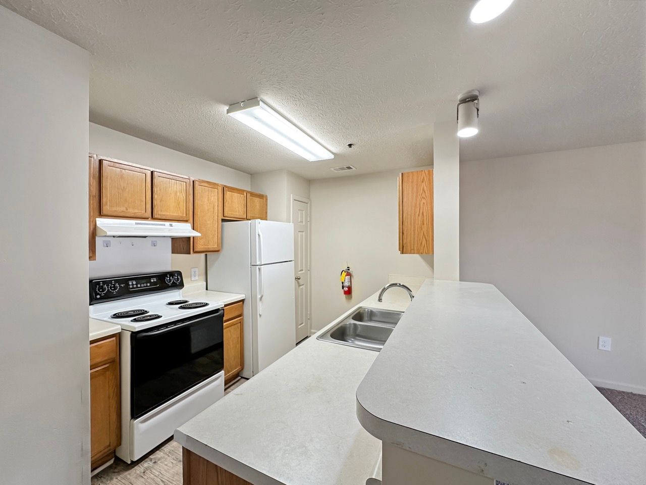 Kitchen with white appliances, wooden cabinets, and a breakfast bar.