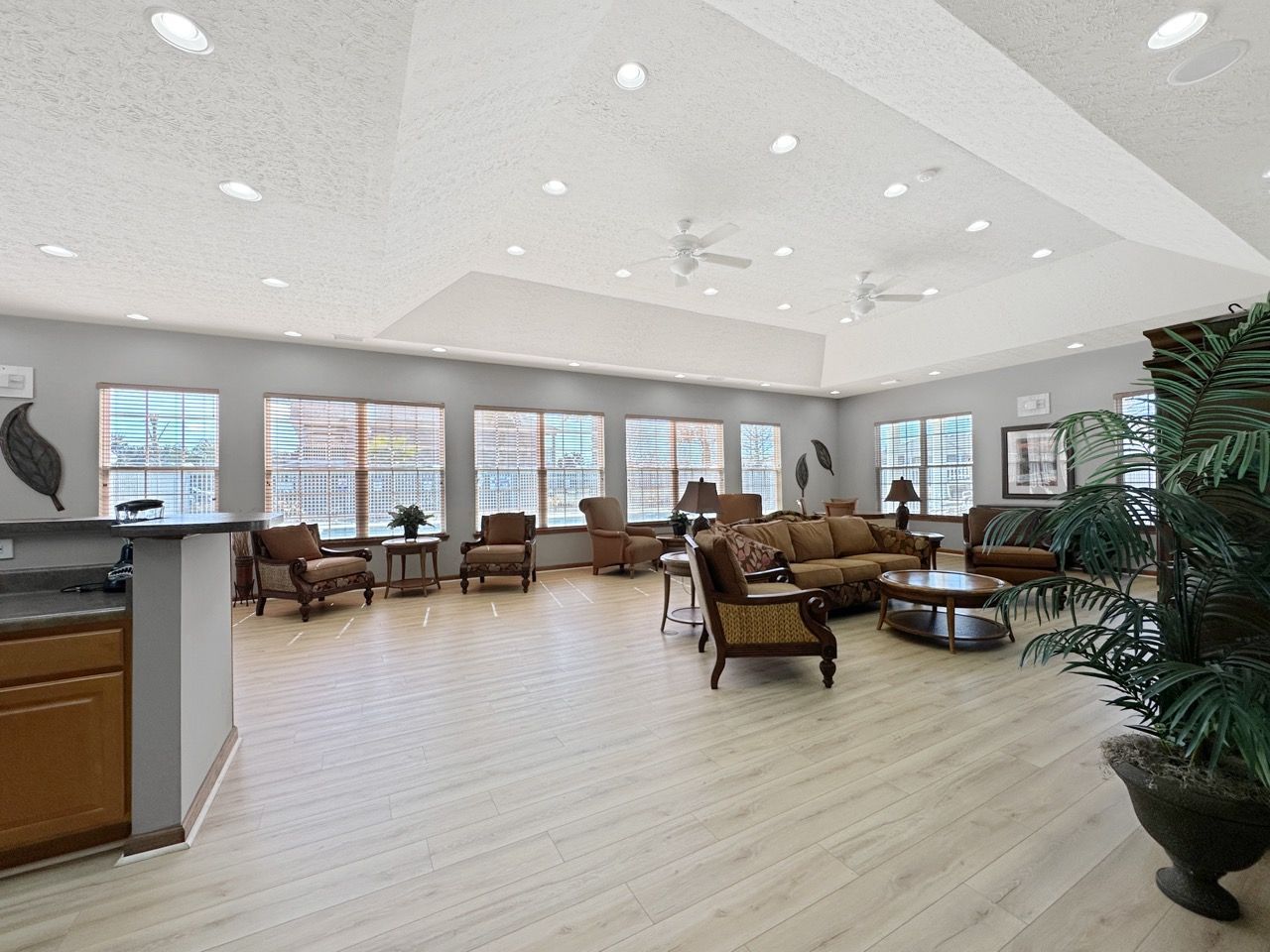 Spacious living room with tan flooring, multiple seating areas, and large windows.