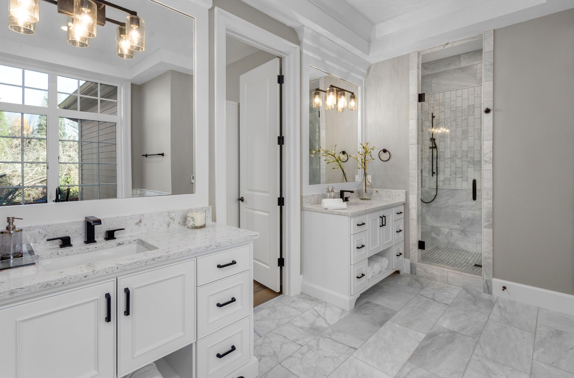 Bright white bathroom with double vanity, marble floors, large mirror, and glass walk-in shower