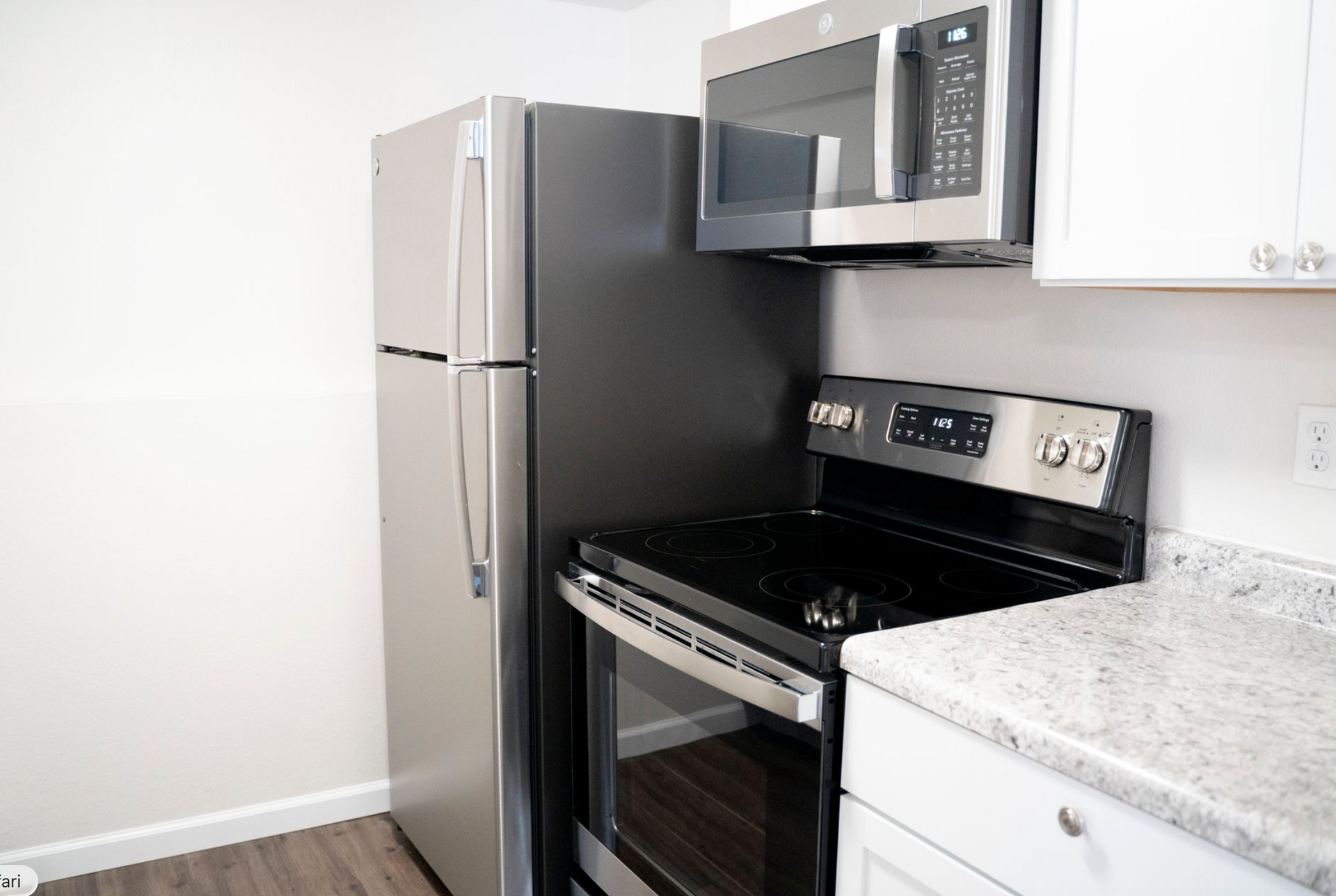 Kitchen with stainless steel refrigerator, microwave, range, and white cabinets.