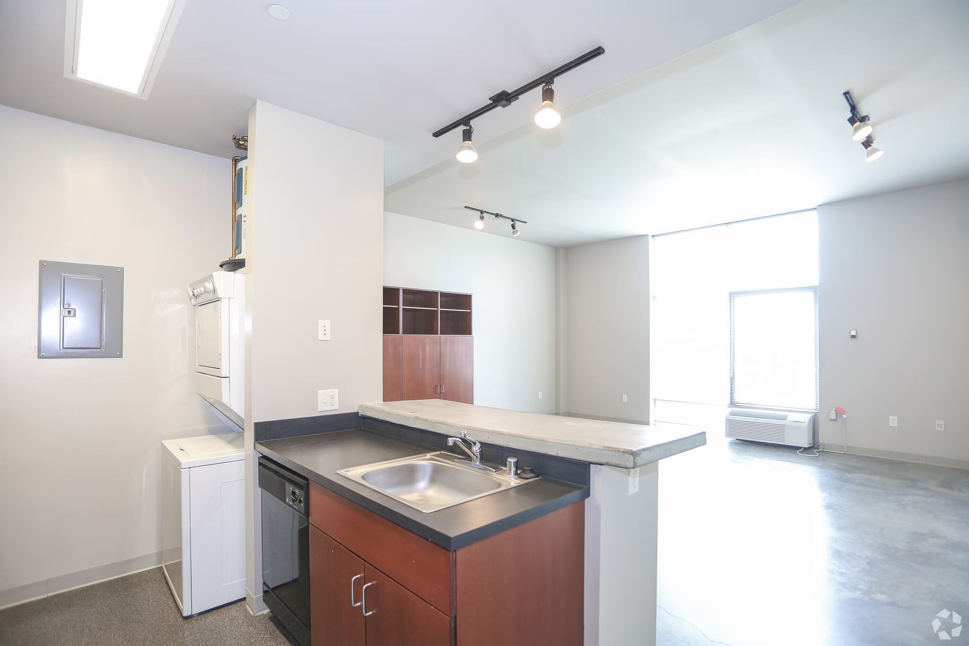 Interior of an empty kitchen with dark cabinets, a sink, and a breakfast bar.