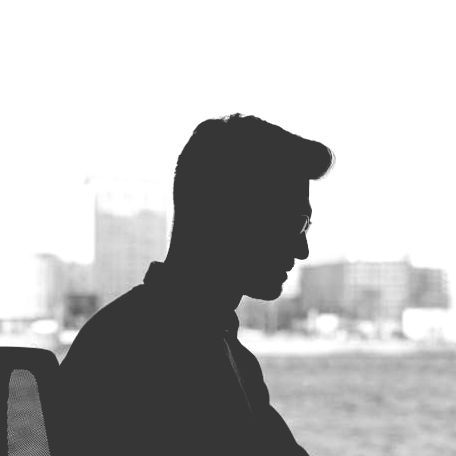 A silhouette of a man sitting in front of a window