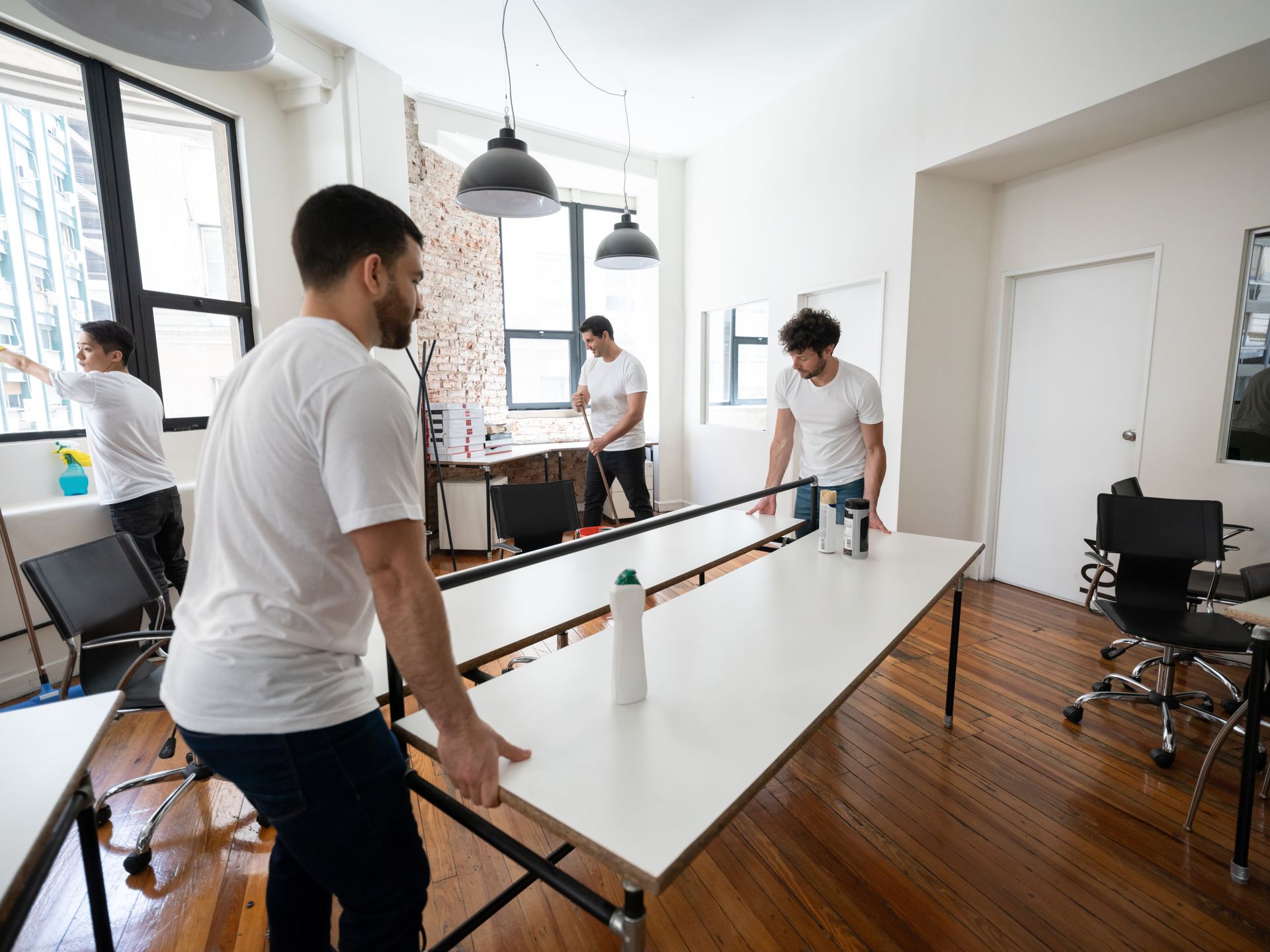 A group of men are cleaning a table in an office.