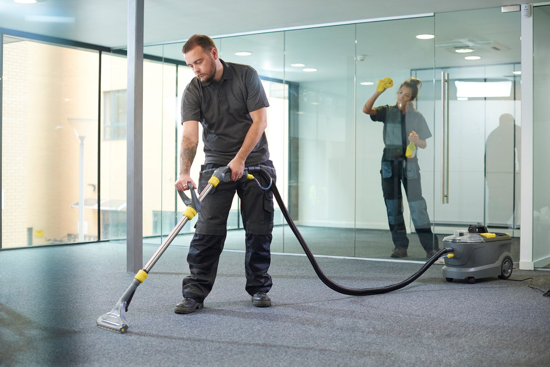 A man is using a vacuum cleaner to clean a carpet in an office.