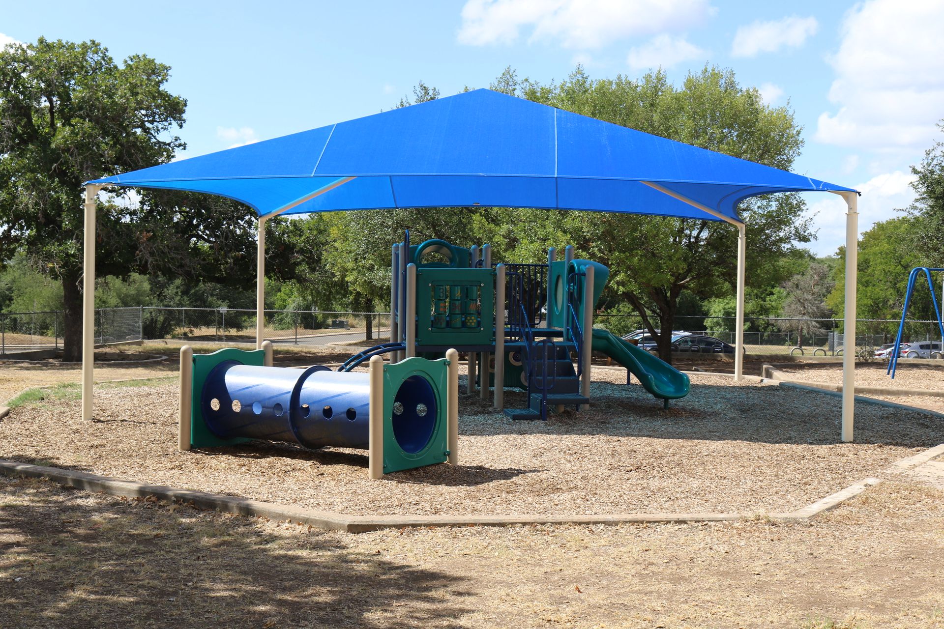 A playground with a blue umbrella over it