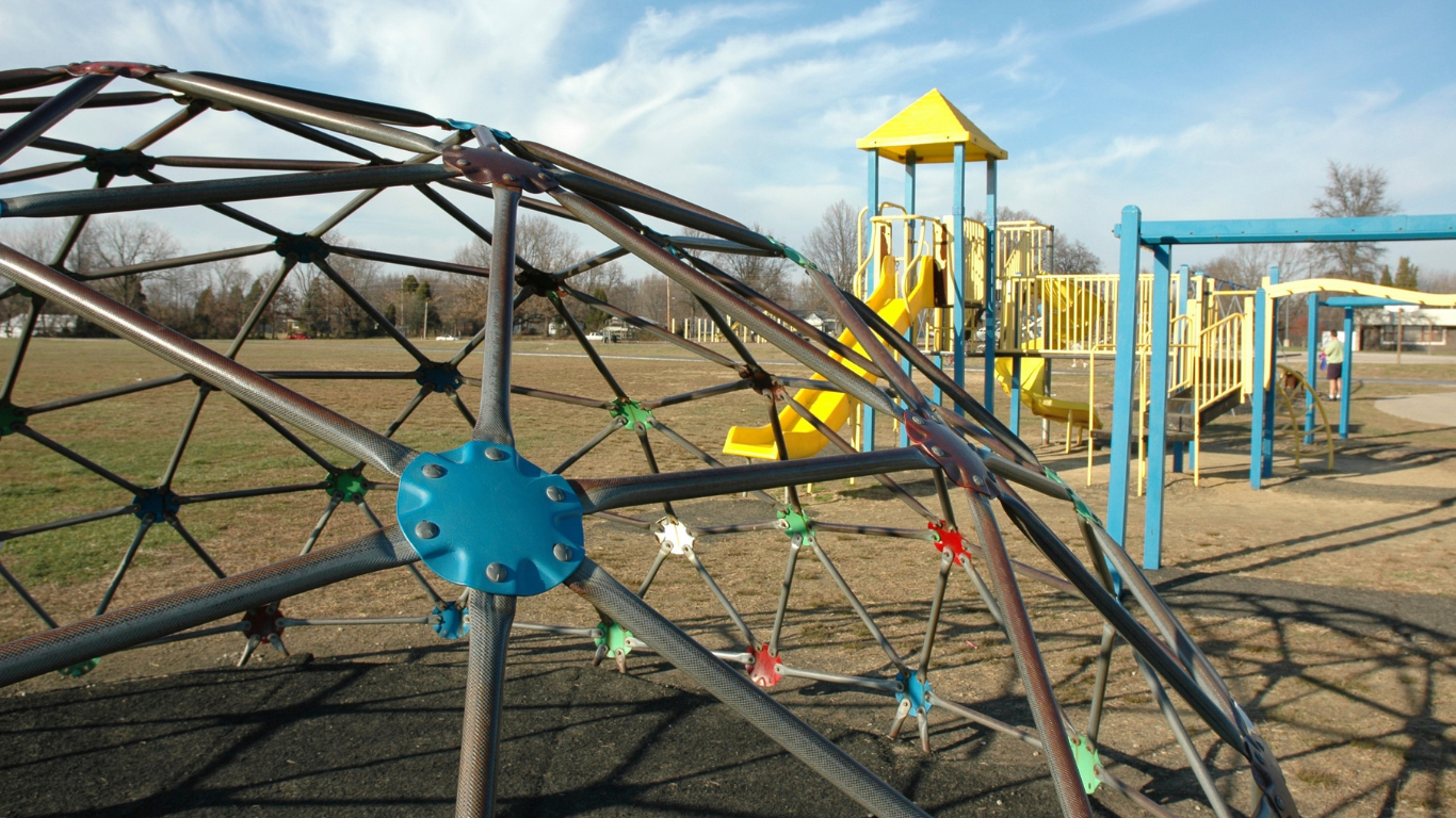 a playground with a yellow slide and a blue swing set