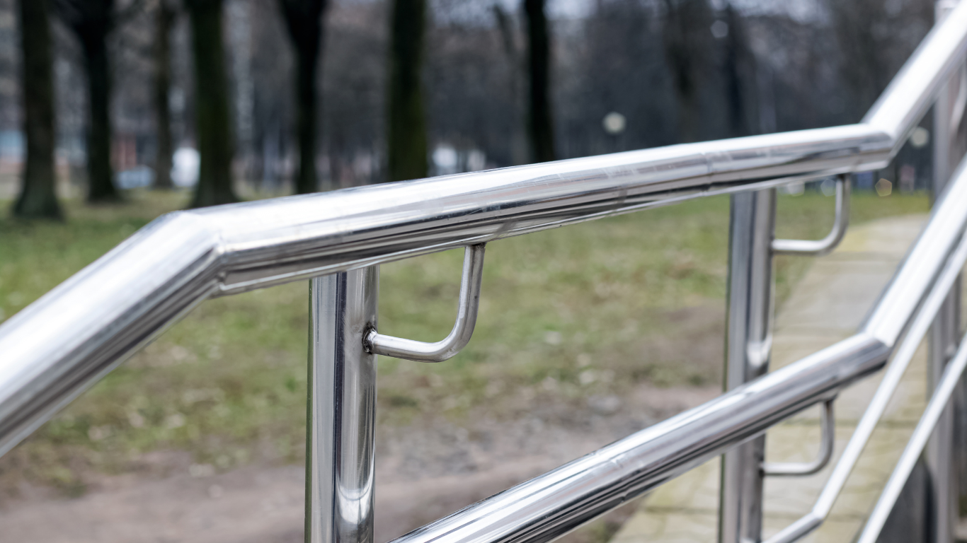 a close up of a stainless steel railing with trees in the background