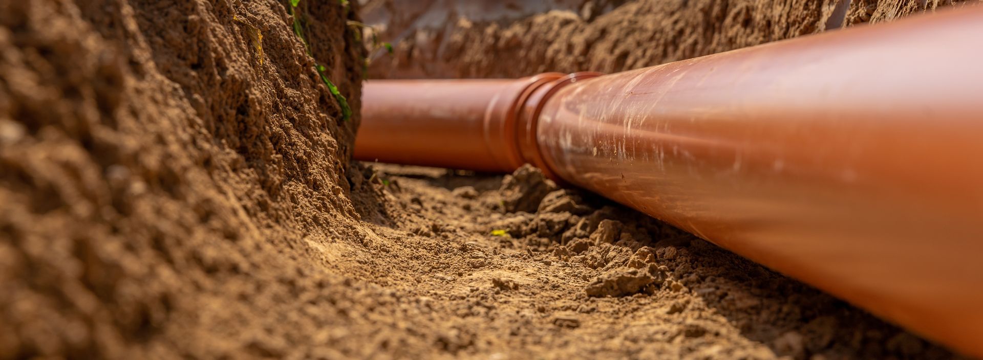 Orange pipeline running through a dug dirt trench