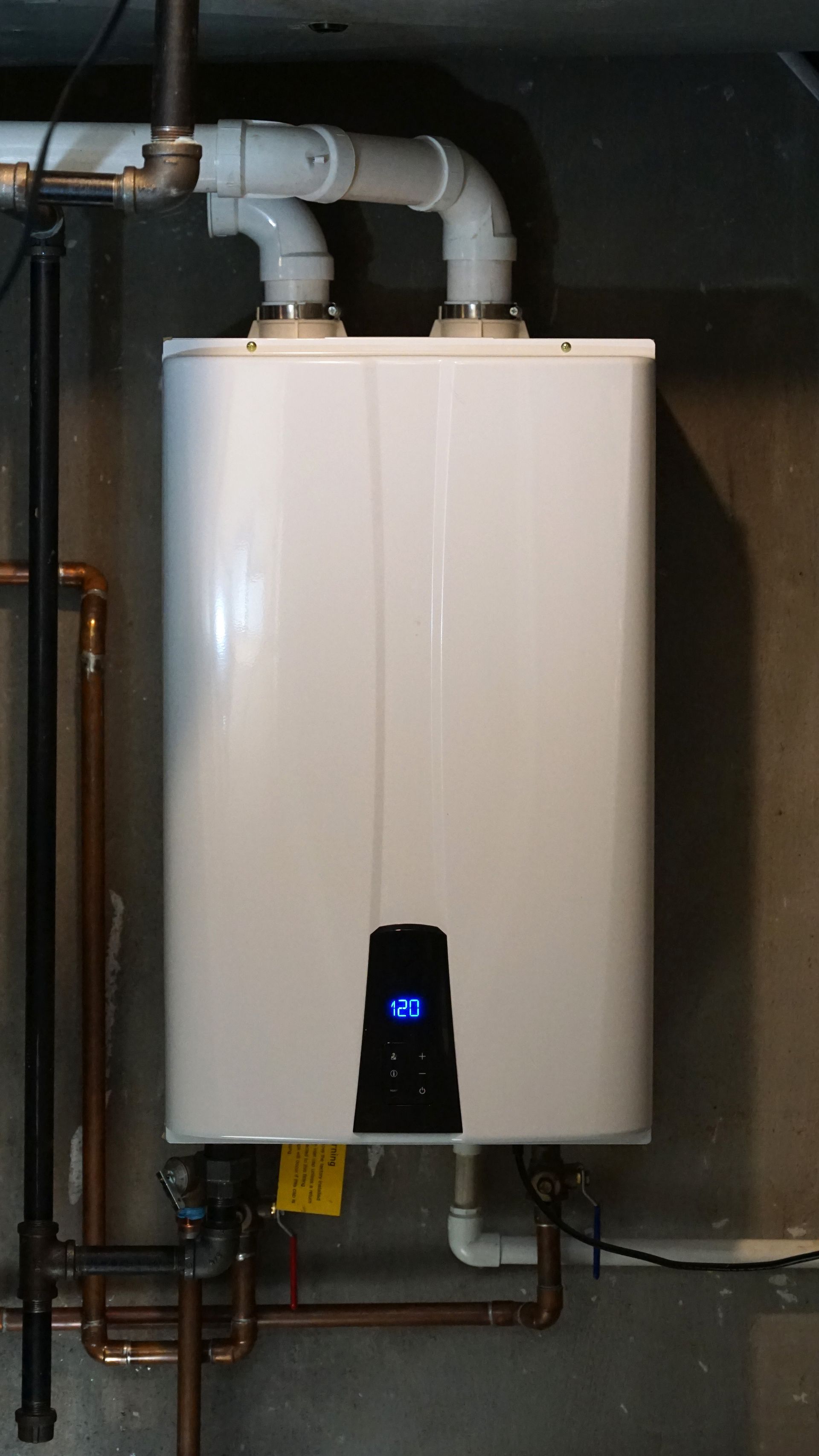 A tankless water heater is installed in a boiler room.