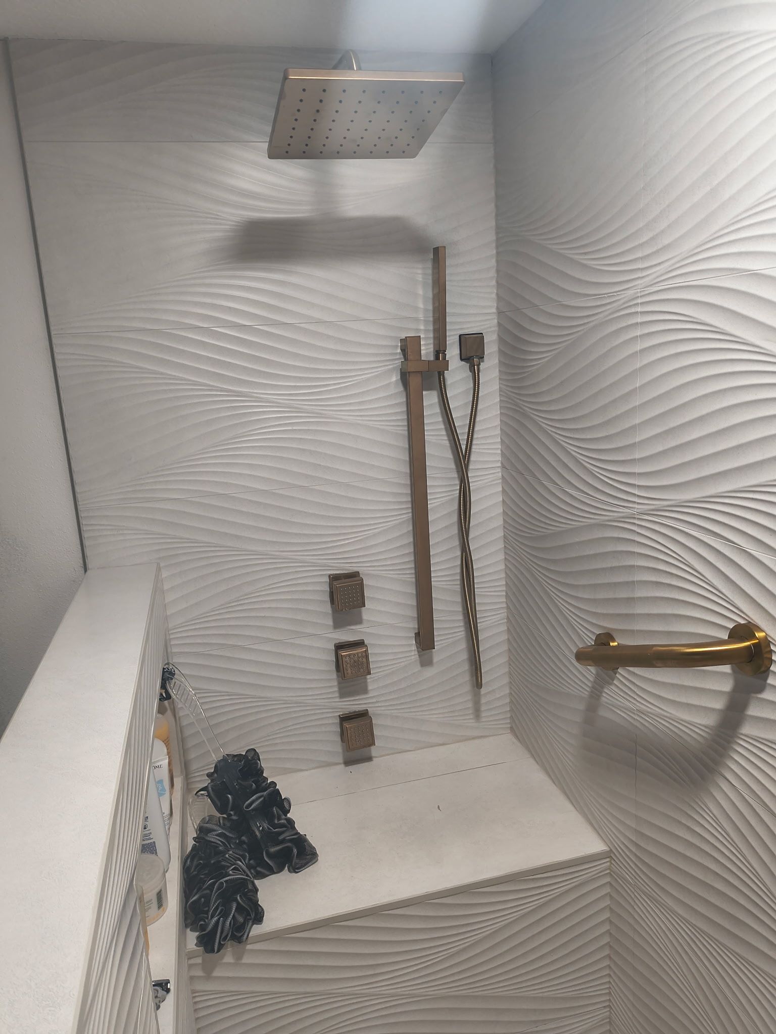 Hands using a red pipe wrench to tighten black plumbing under a sink