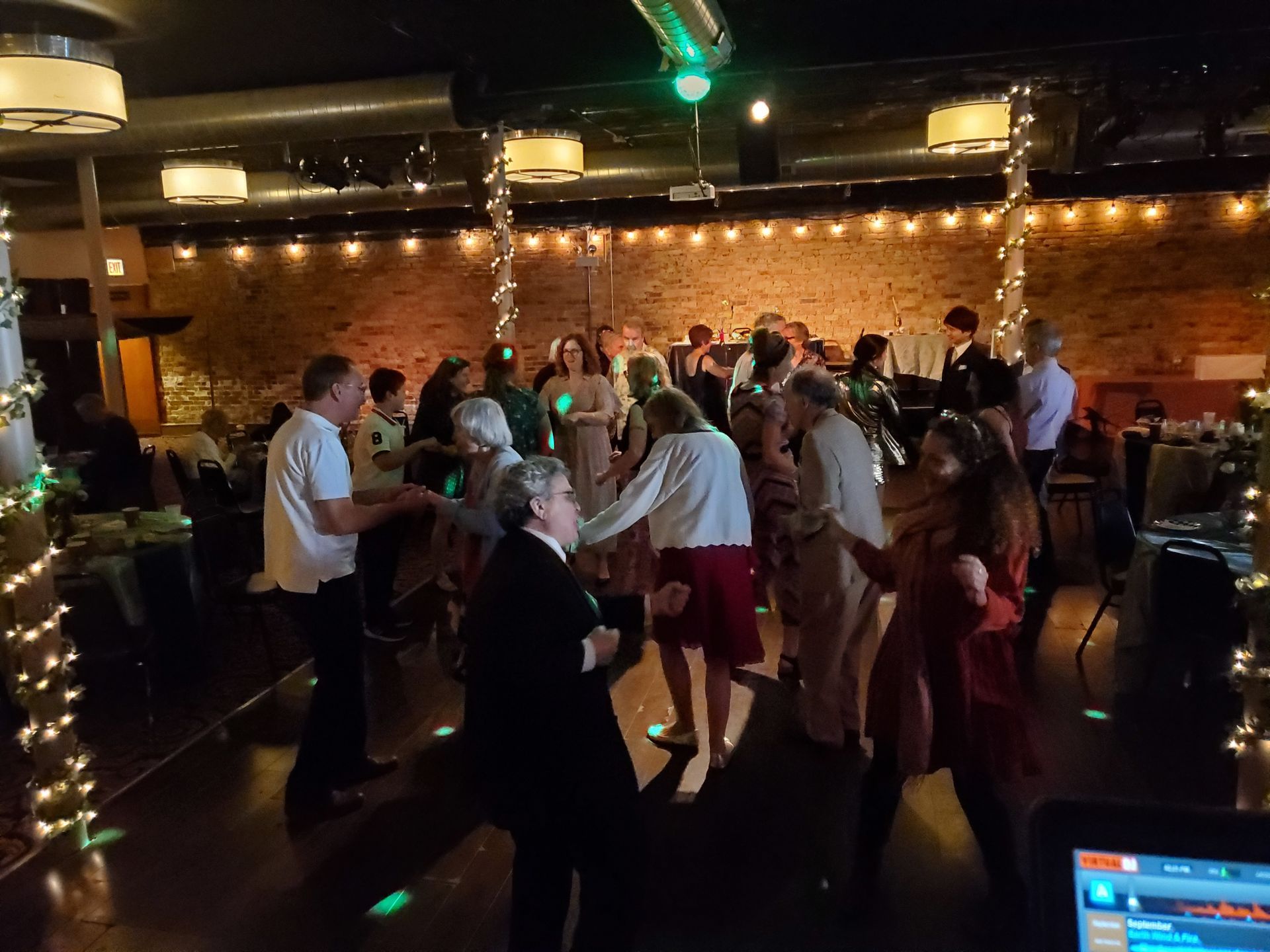 A group of people are dancing in a room at a wedding reception.