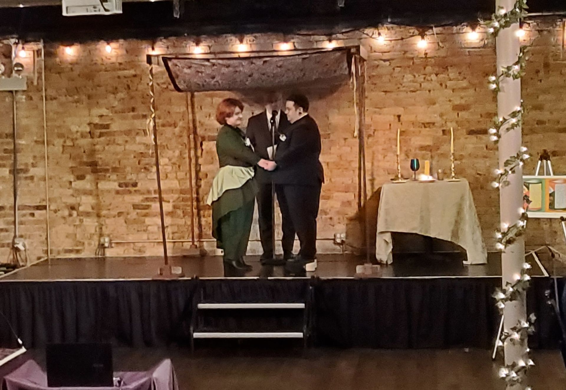 A man and a woman are standing on a stage holding hands.