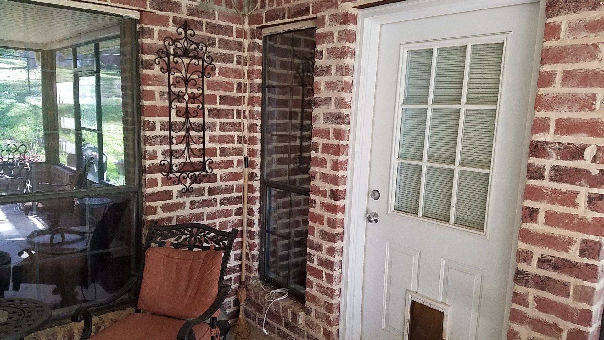 A brick porch with a chair and a white door