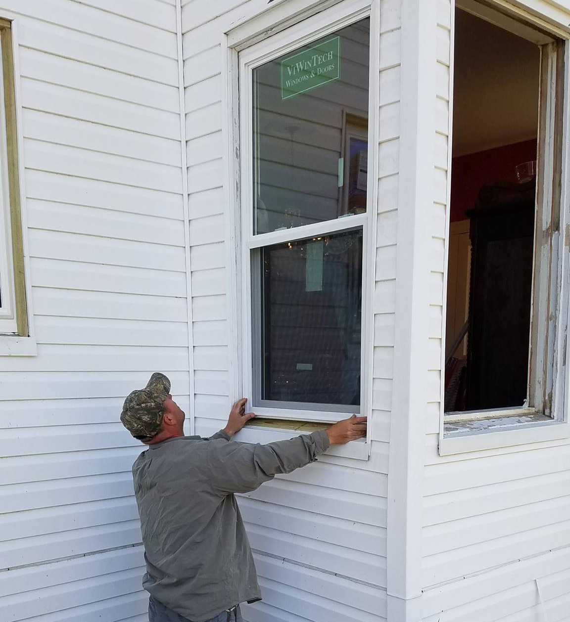 A man is fixing a window on a white house