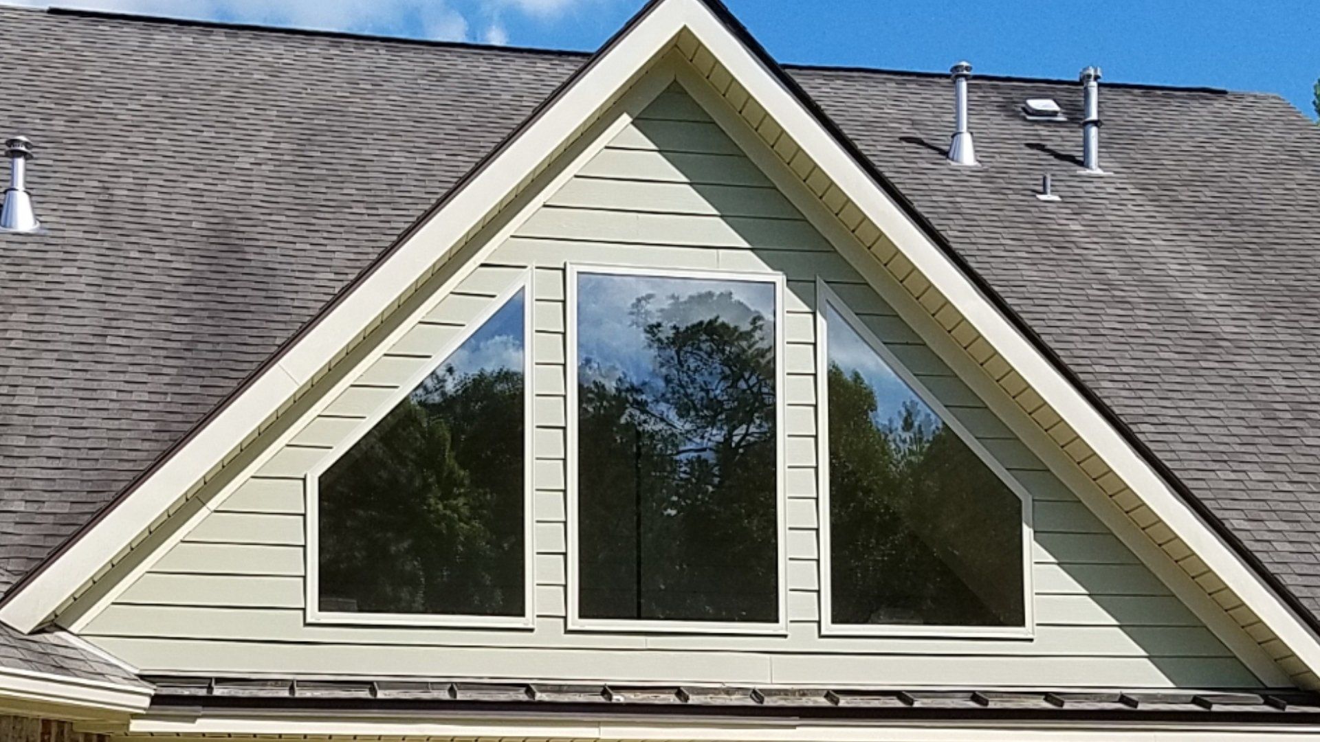 A house with a triangle shaped roof and three windows
