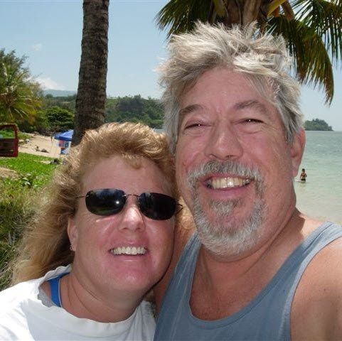 A man and a woman are posing for a picture on the beach