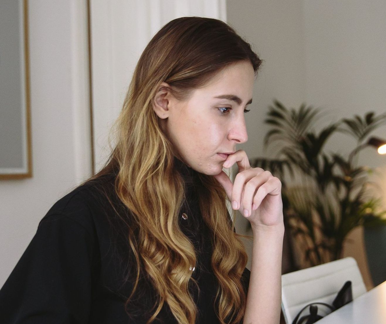 A woman sitting at a desk with her hand on her chin