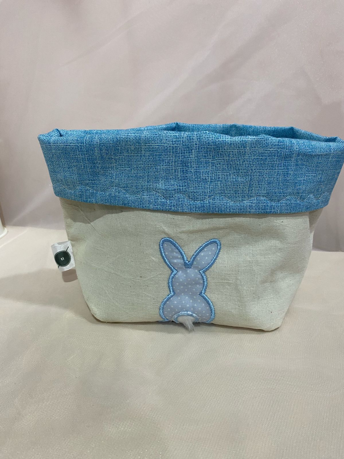 Papelera de tela blanca con forro interior de lunares rojos, plegada.