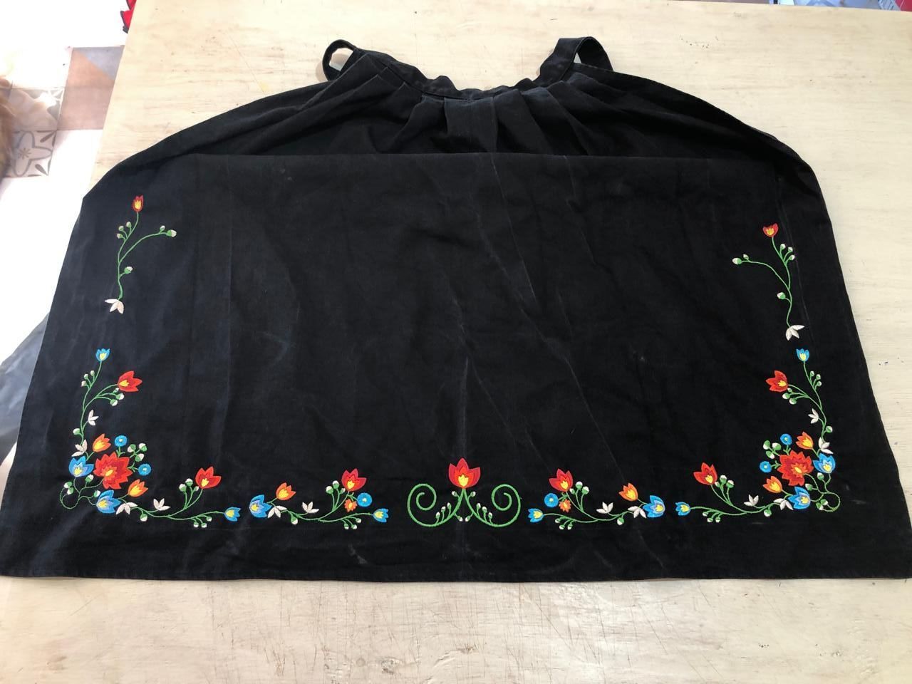 Delantal azul marino con rayas verticales blancas y tirantes rayados sobre hierba.