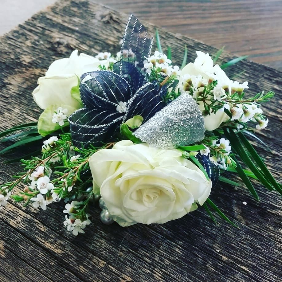 a Boutonnière of white roses with a black and silver bow